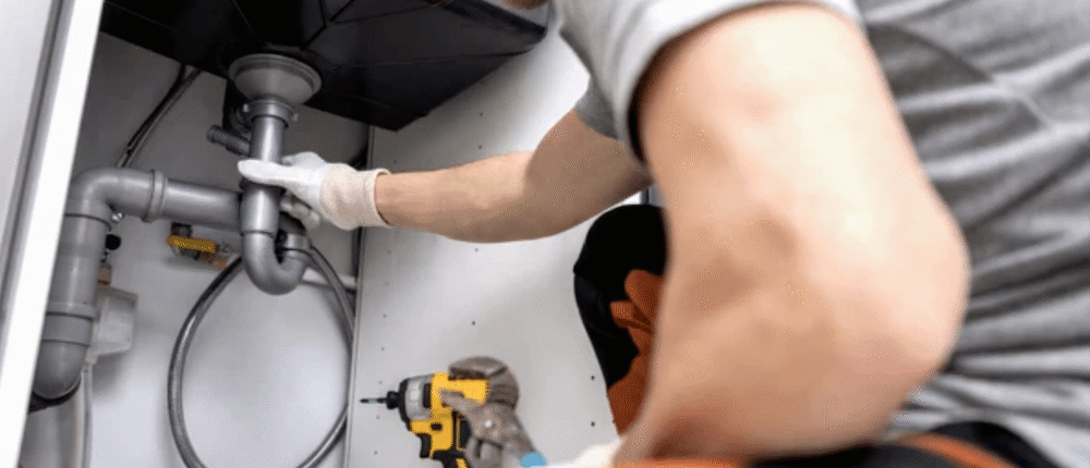 A professional plumber cleaning a clogged drain line using specialized tools.