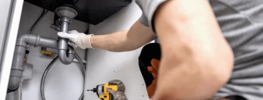 A professional plumber cleaning a clogged drain line using specialized tools.