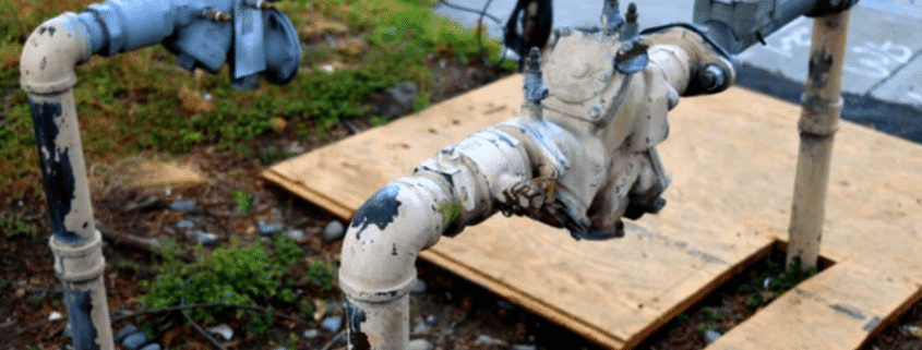 Backflow preventer device installed on residential water supply line with test ports visible