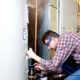 A technician is repairing a residential electric water heater in a utility room.